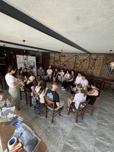 Групна фотографија од обуката „Визија за инклузија“ во Крушево, со учесници седнати во круг, а во позадина се банери со логото на НССРСМ и Еразмус +